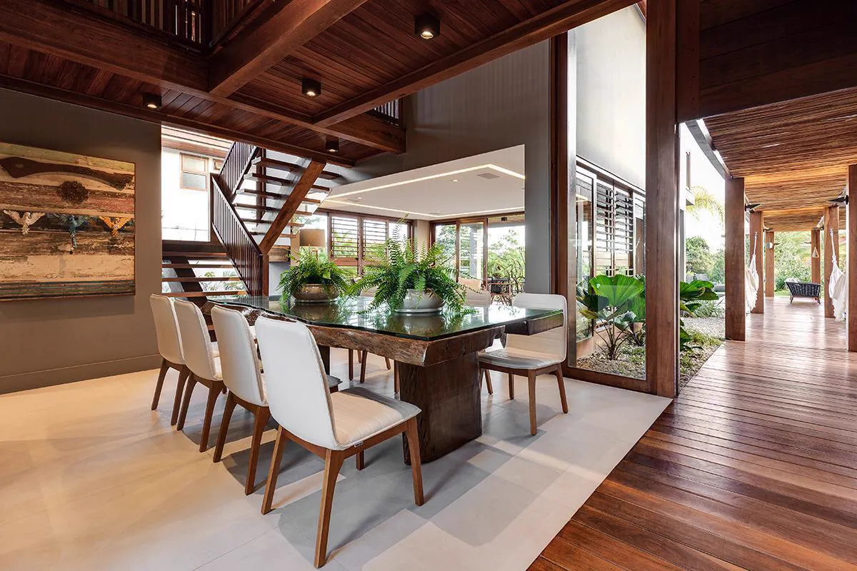 Sala de jantar com teto em vigas de madeira e vista para a varanda
