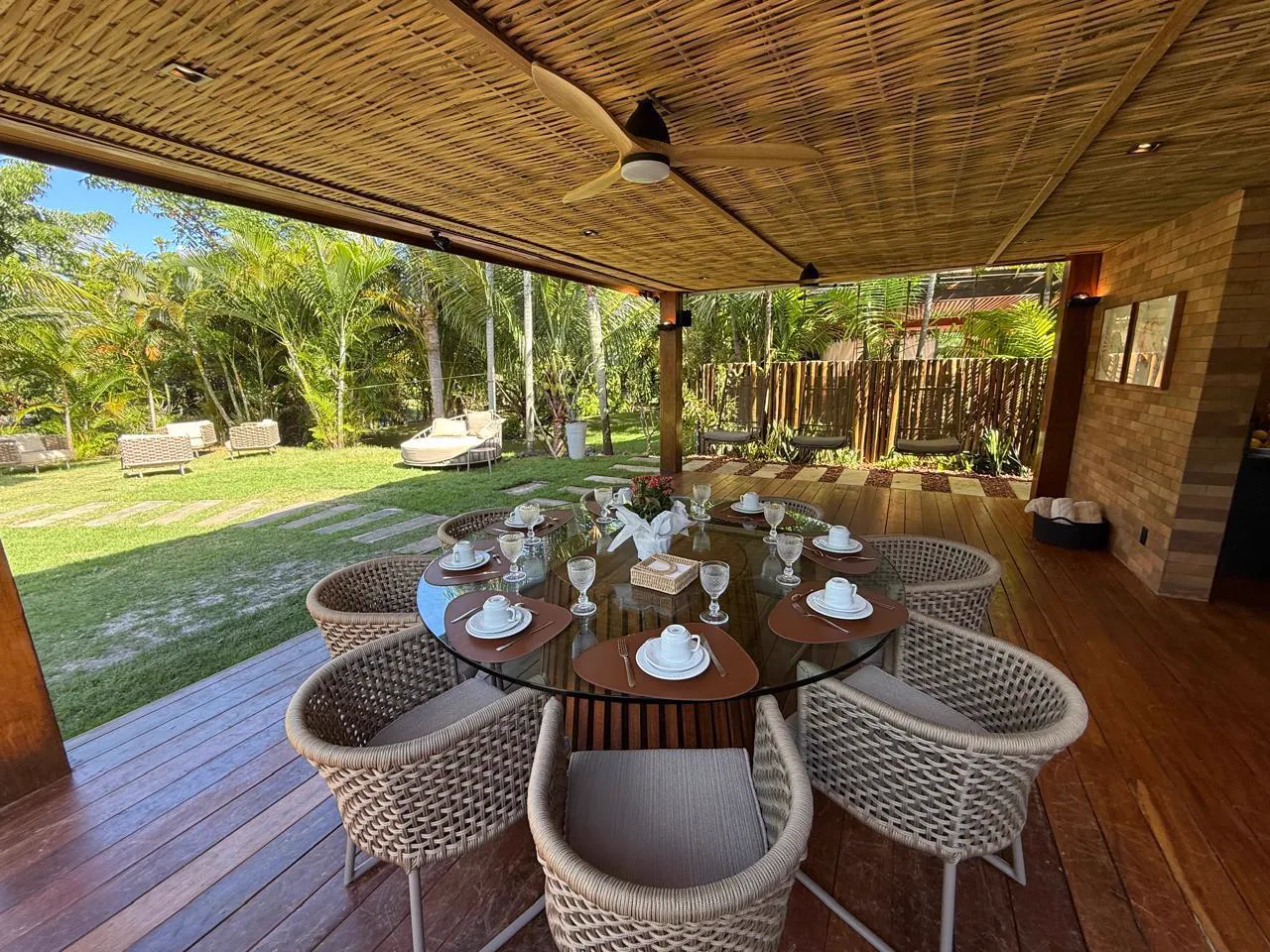 Deck coberto com mesa de jantar, de frente para o jardim